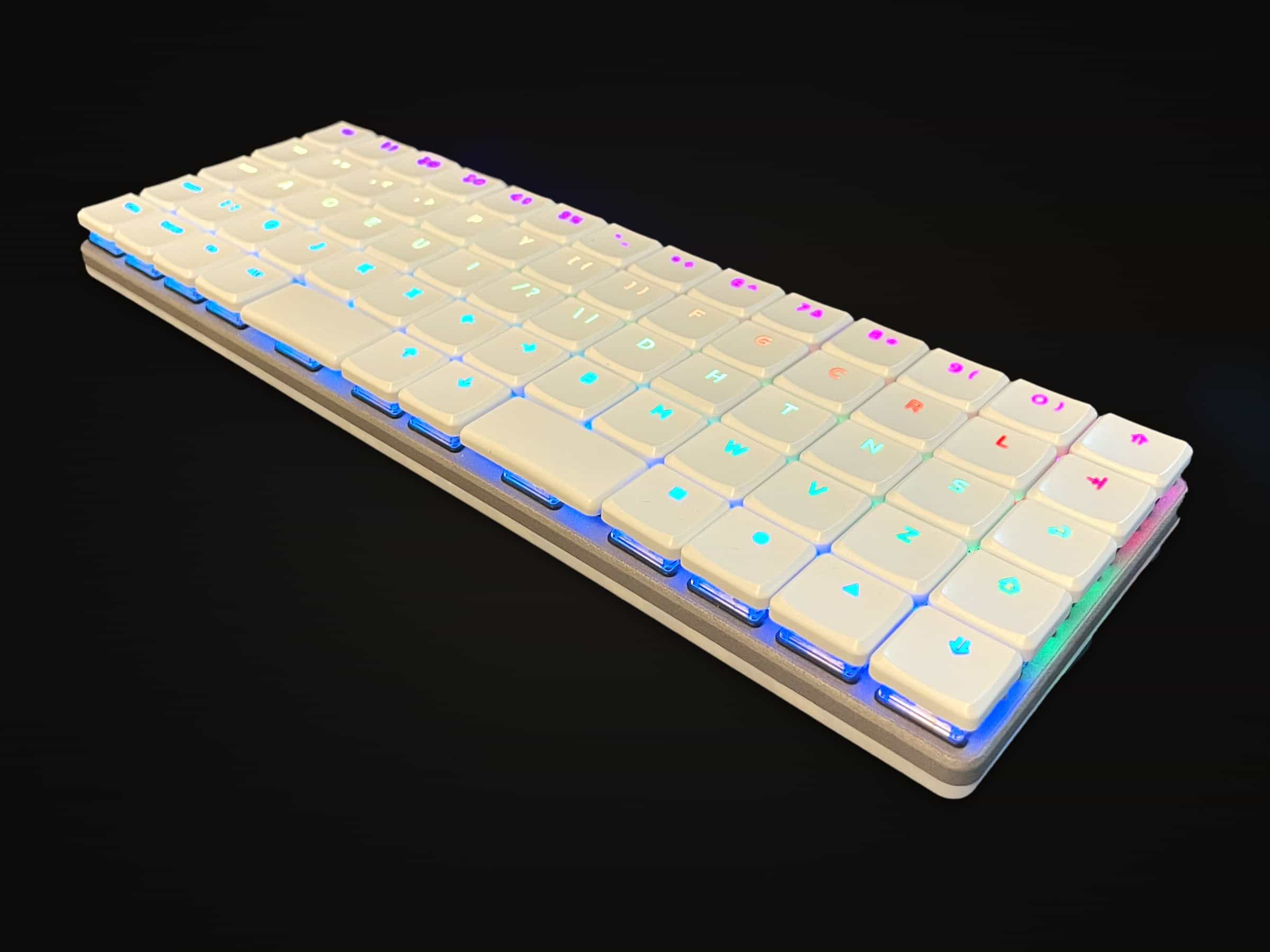 KeBe v1 in white, its shine-through legends lit in a rainbow.
