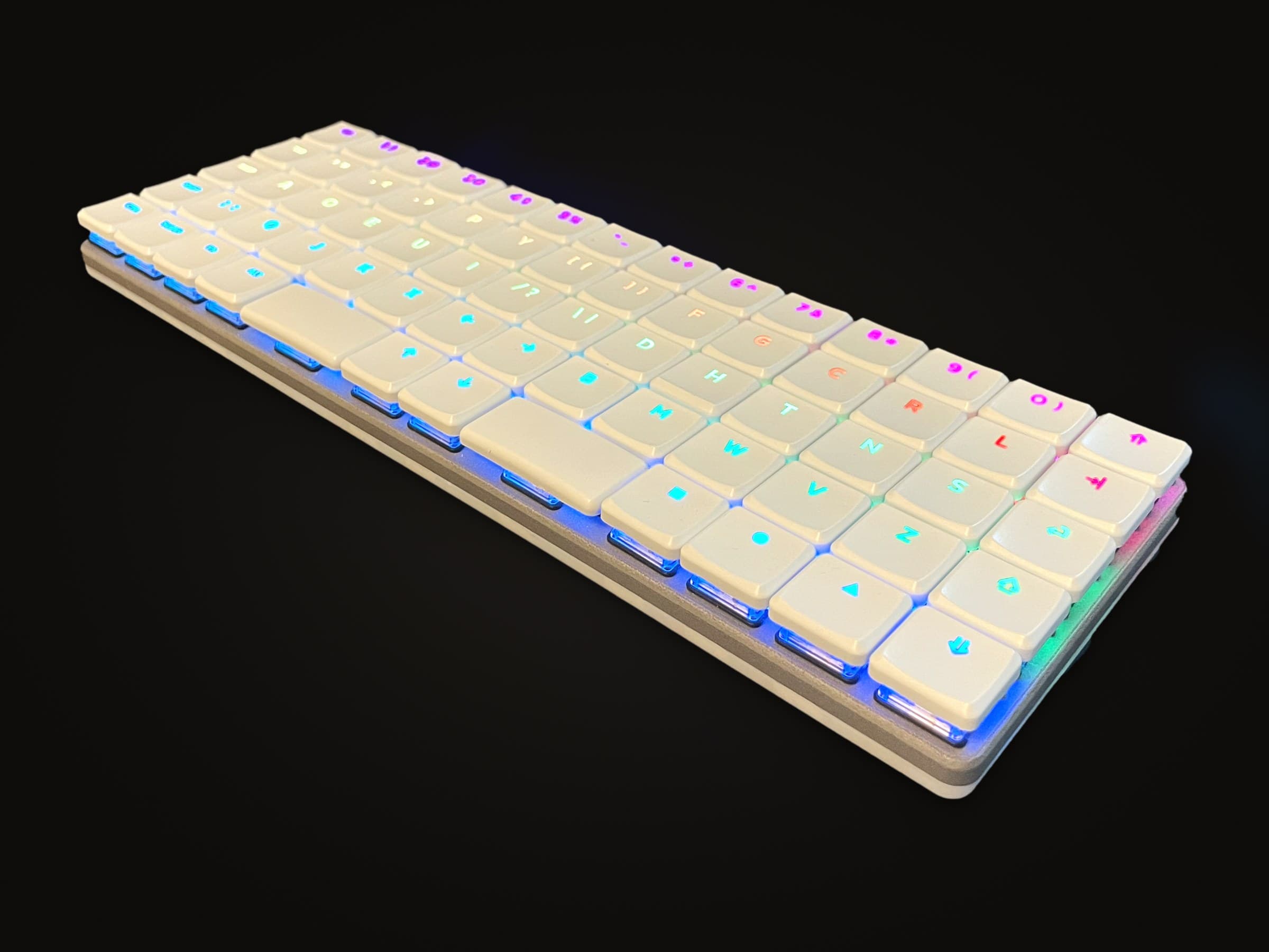 KeBe v1 in white, its shine-through legends lit in a rainbow.